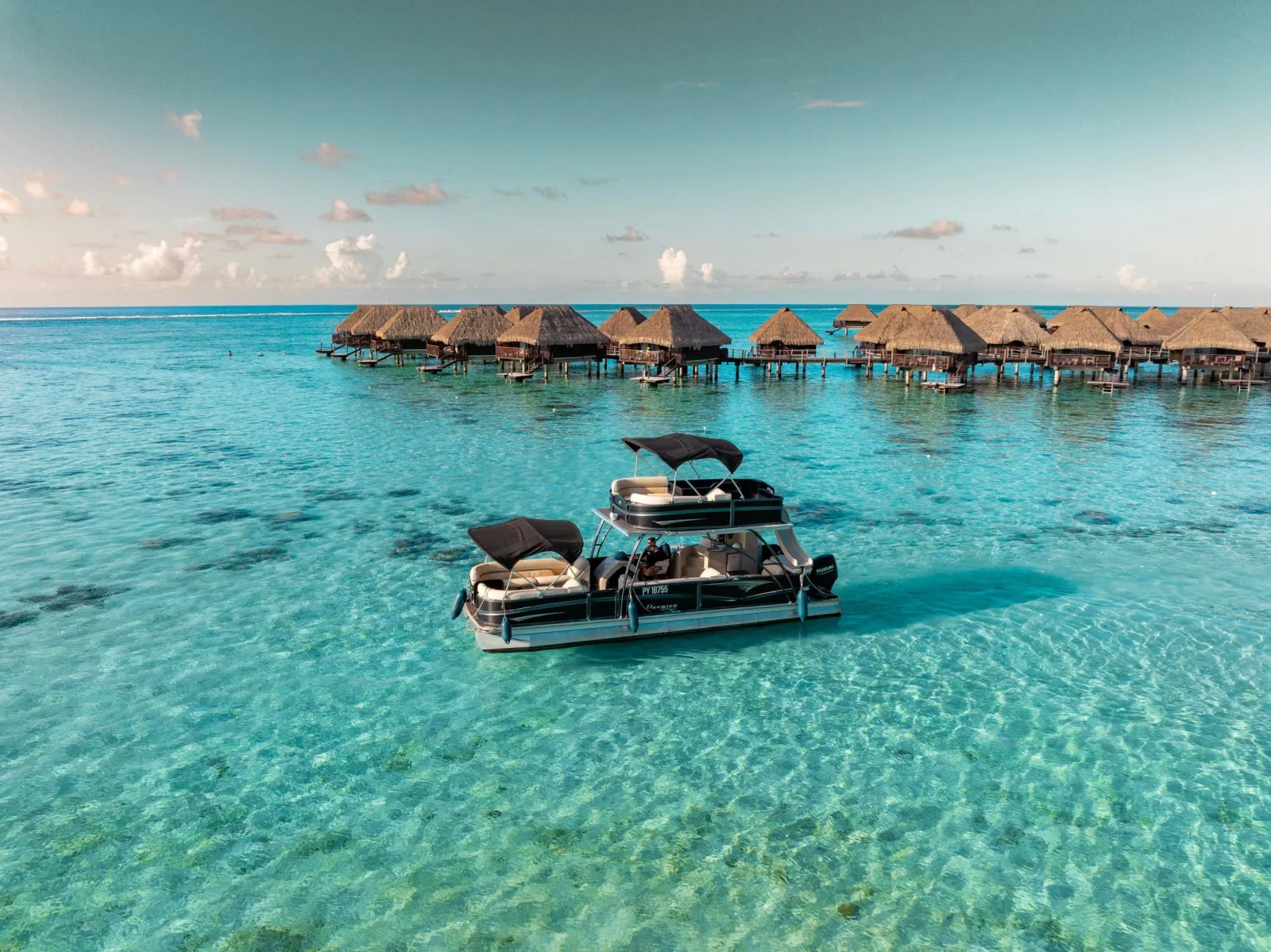 Pontoon boat in the lagoon in front of a row of overwater bungalows