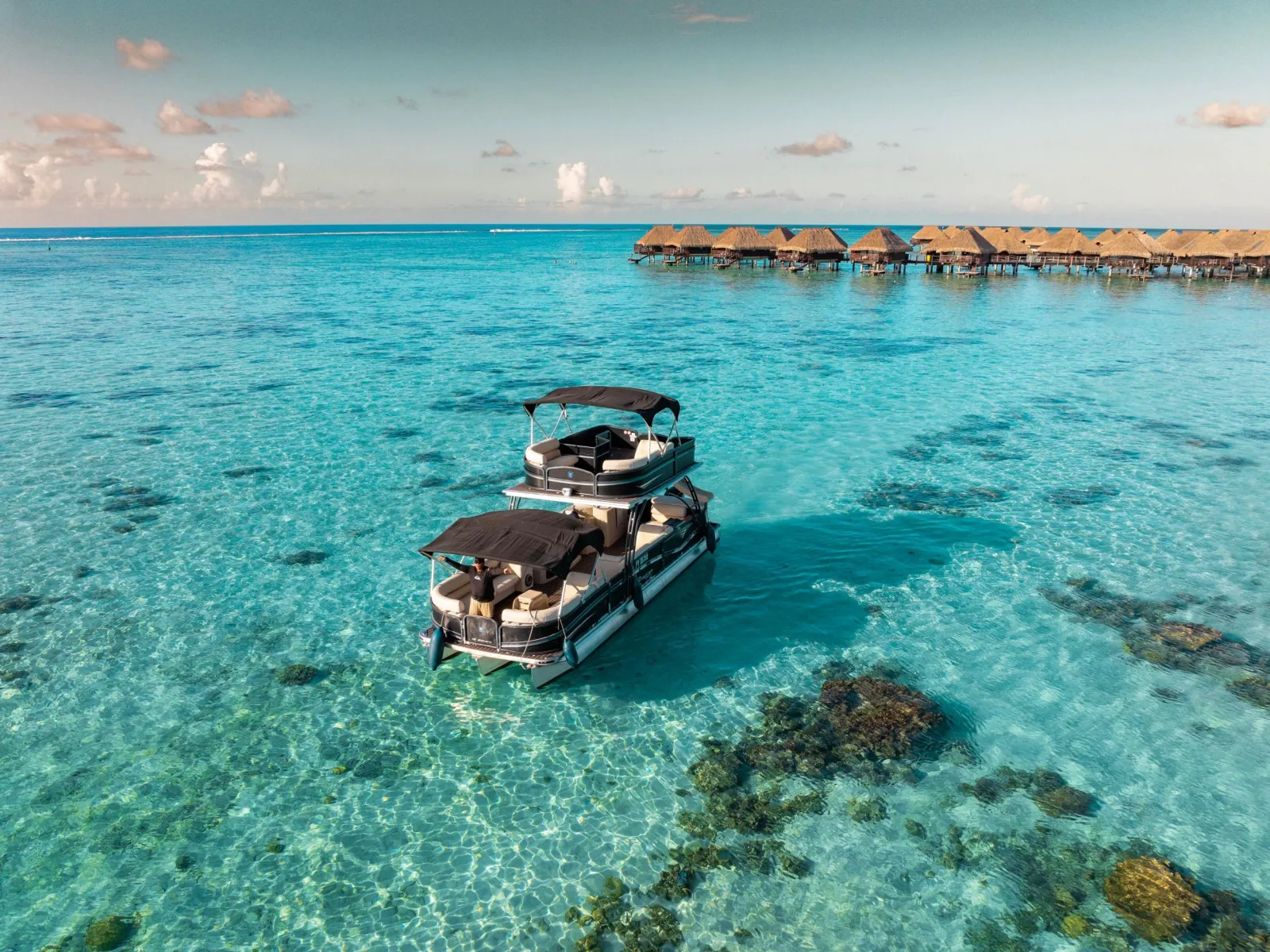 Pontoon boat over coral heads with overwater bungalows in the distance