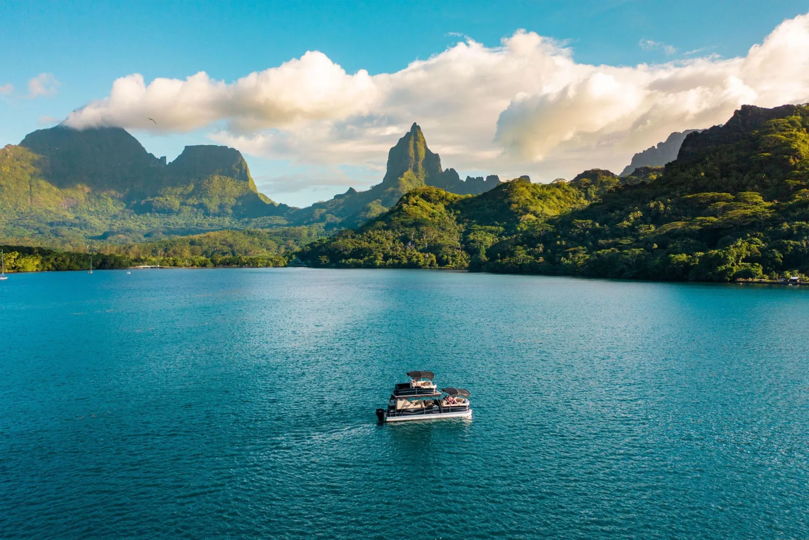 Pontoon boat crossing a Moorea bay below the island's jagged peaks