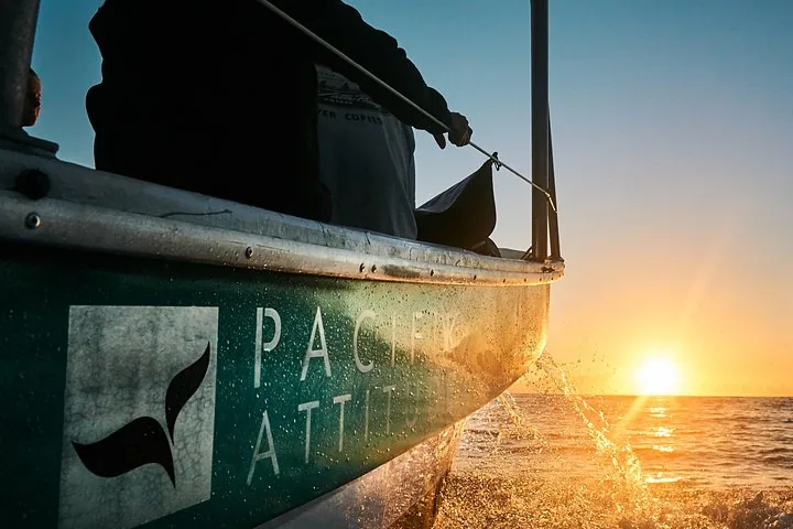 Bow of the Pacifik Attitude boat throwing spray at sunrise