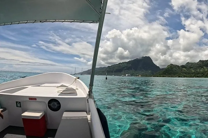 Bow of the boat with a red cooler, crossing the clear lagoon toward Moorea's mountains