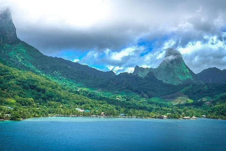 Moorea's bay and jagged green peaks seen from the water under clouds