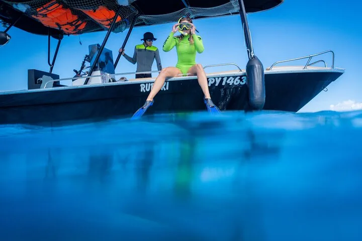 Guest in a snorkel mask sitting on the side of the Wild Explorer boat